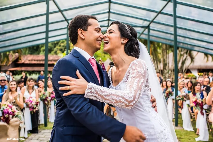 Casal de noivos sorrindo durante a cerimônia ao ar livre no Lajedo